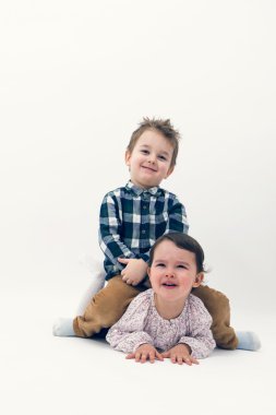 Küçük yürümeye başlayan çocuk, kız kardeşinin sırtına at binme