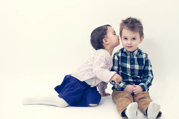 Kleines Mädchen küsst ihren älteren Bruder isoliert auf die Wange — Stockfoto