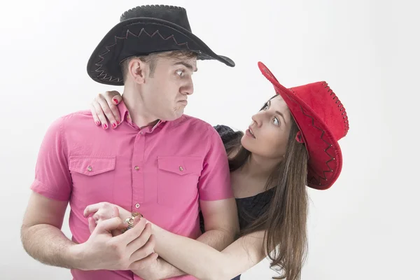 Casal jovem com chapéus de cowboy fazendo caras bobas no fundo branco — Fotografia de Stock