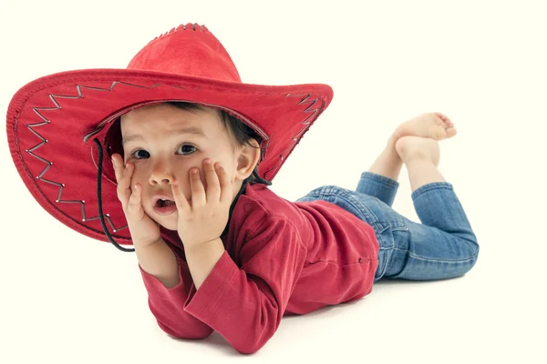 Little cowgirl i en röd hatt poserar på en vit bakgrund — Stockfoto
