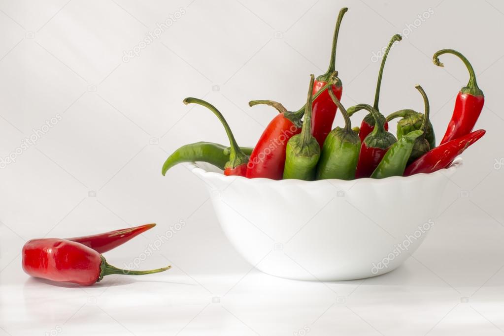 Red and green hot chili pepper in a ceramic bowl isolated