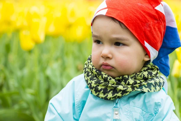 Schöne kleine Mädchen mit einem Feld von Tulpen im Hintergrund — Stockfoto