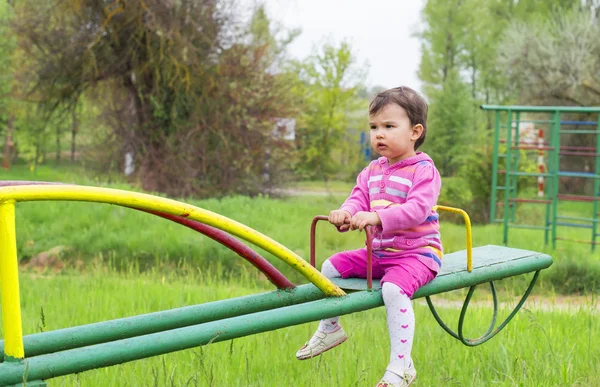 Lilla söta tjejen sitter på gungbräda i en solig dag — Stockfoto