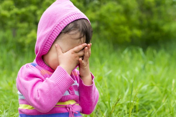 Little girl is playing hide-and-seek hiding face — Stock Photo, Image