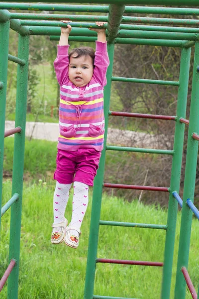 Menina feliz escalando no playground ao ar livre — Fotografia de Stock