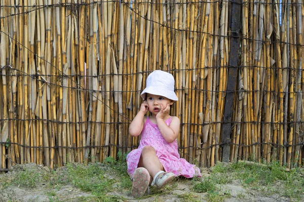 Upprörd liten flicka som täcker hennes mun med palmer och tittar åt sidan — Stockfoto