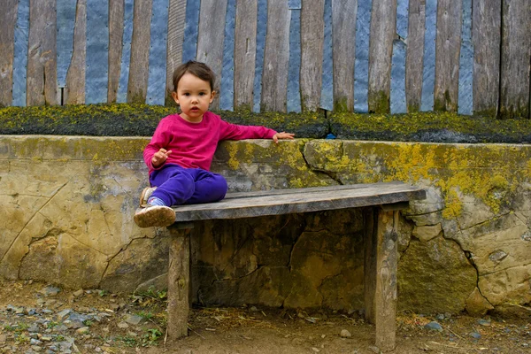 Two years old  girl sitting on rustic bench — Stock Photo, Image