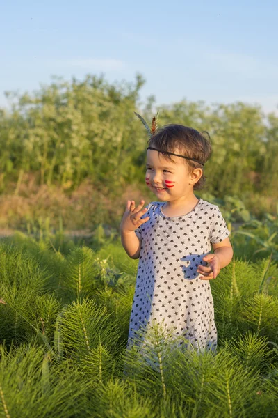 Lustiges kleines Mädchen als Indianerin mit Maracas und Feder — Stockfoto