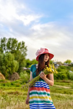 Alan tutan genç bir kadın ayakta portresi giyen kırmızı şapka çiçekler