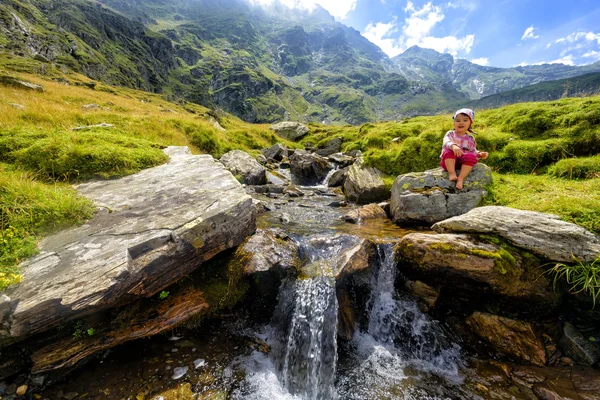 Una niña pequeña admirando un arroyo de montaña — Foto de Stock