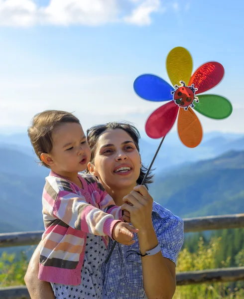 Nyári ünnepek, család, gyermekek és az emberek koncepció - boldog anya és a gyermek lány játék pinwheel — Stock Fotó