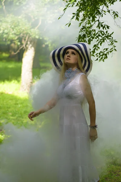 Blonde lady with big summer hat surounded by smoke — Stock Photo, Image