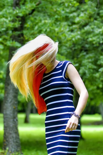 Блондинка с красным шарфом и полосатым платьем — стоковое фото