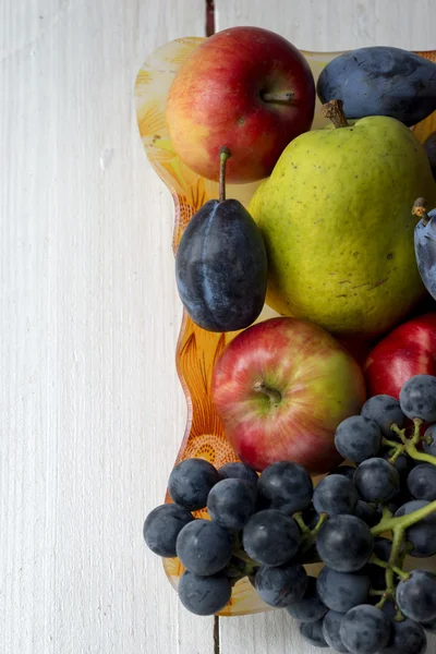Cesta llena de frutas. Peras, manzanas, uvas y ciruelas —  Fotos de Stock