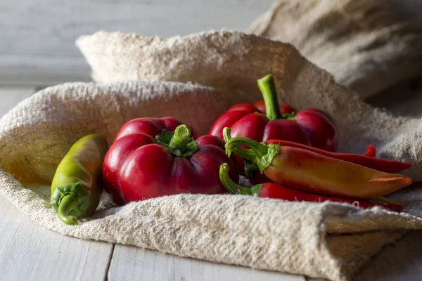 Röd paprika och peppar på ett träbord — Stockfoto