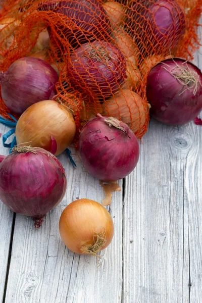 Red and yellow onion on wooden surface — Stock Photo, Image