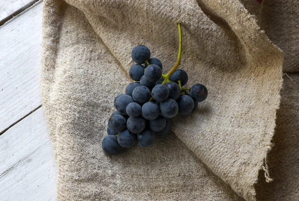 Bunch of blue grapes on wooden background and cloth — Stock Photo, Image