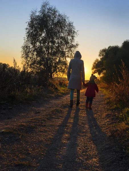 Anya és lánya séta országúton naplementekor — Stock Fotó