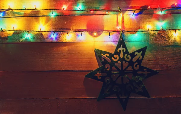 Luzes de Natal e estrela no fundo de madeira — Fotografia de Stock