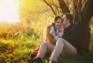 Oturma ve öpüşme genç çift ormanda yakınındaki