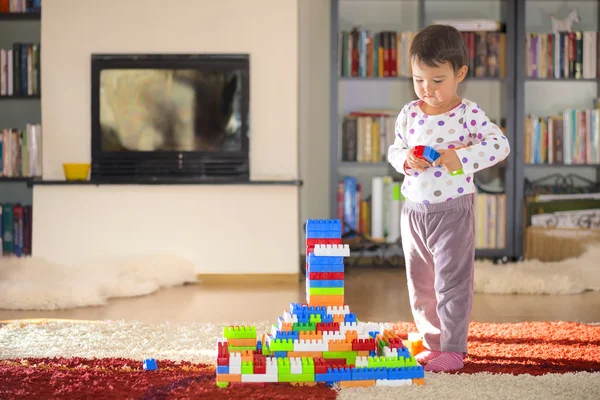 Brunett tjej i förskoleåldern leker med färgglada blocken sitter på ett golv — Stockfoto