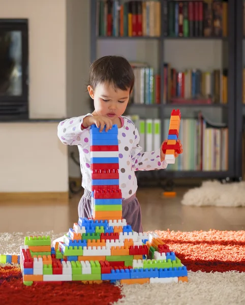 Brunette girl of preschool age playing with colorful blocks sitting on a floor — Stock Photo, Image