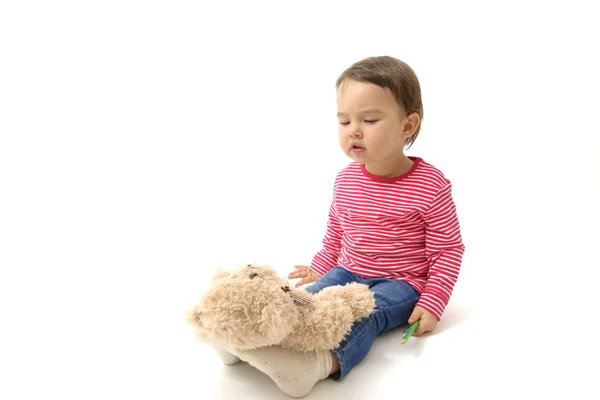 Sweet  toddler girl playing with her teddy bear putting him on feet to sleep — Stock Photo, Image