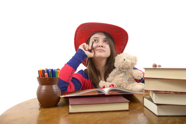 Niña meditativa con sombrero rojo y su osito de peluche en la mesa con libros —  Fotos de Stock