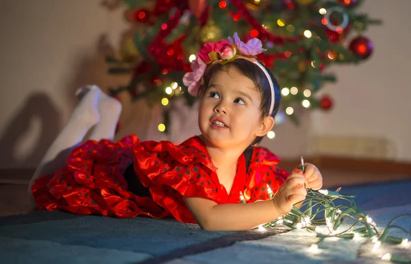 Очаровательная маленькая девочка играет с рождественскими огнями — стоковое фото
