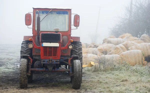 Rode trekker in mistige veld in de ochtend — Stockfoto