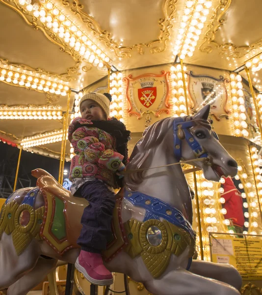 Adorable little girl on a carousel at Christmas market — Stock Photo, Image