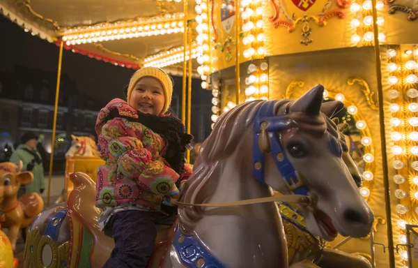 Adorable little girl on a carousel at Christmas market — Stock Photo, Image