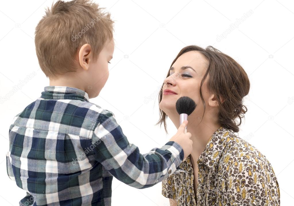 little boy putting on the makeup to her mother