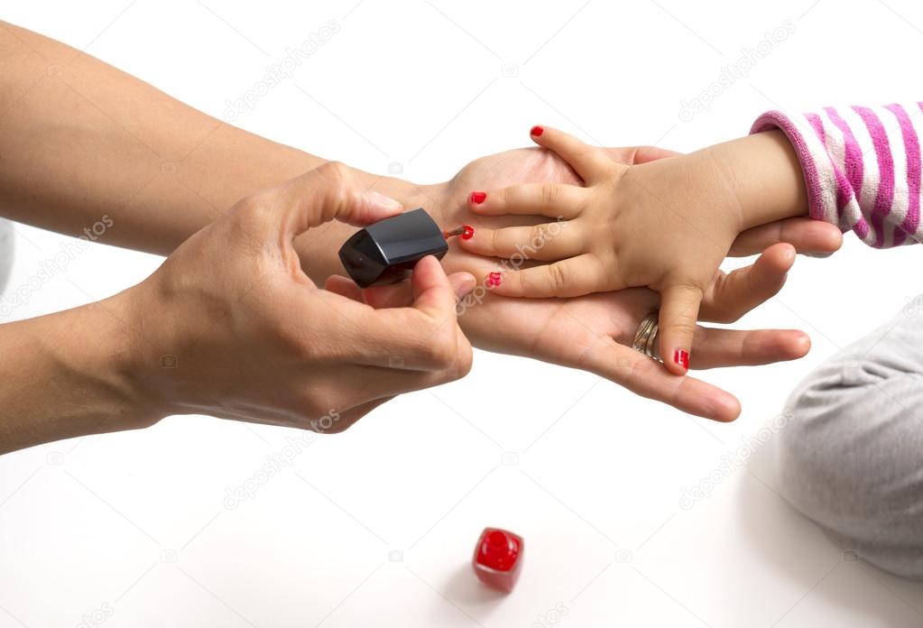 mother applying nail polish to her little girl
