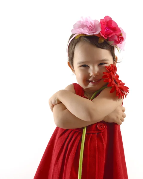 Liten flicka i röd klänning omfattar en röd gerbera — Stockfoto