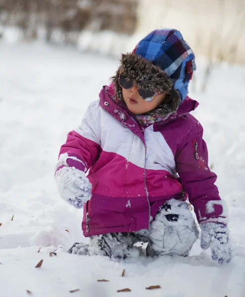 Kaukasiska liten flicka i vinterkläder leker i snön — Stockfoto