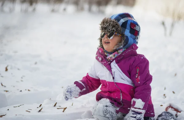 Kaukasiska liten flicka i vinterkläder leker i snön — Stockfoto