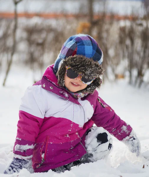 Kaukasiska liten flicka i vinterkläder leker i snön — Stockfoto