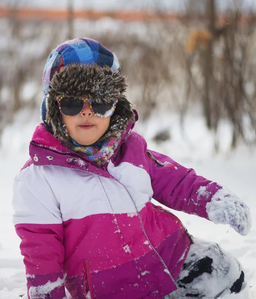 Kaukasiska liten flicka i vinterkläder leker i snön — Stockfoto