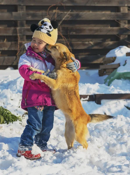 Little girl playing with a mongrel dog in the snow — Stock Photo, Image