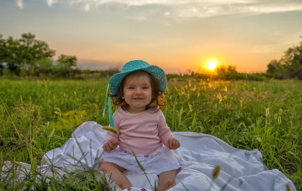 Beautiful baby sitting on blanket at sunset — Stock Photo, Image