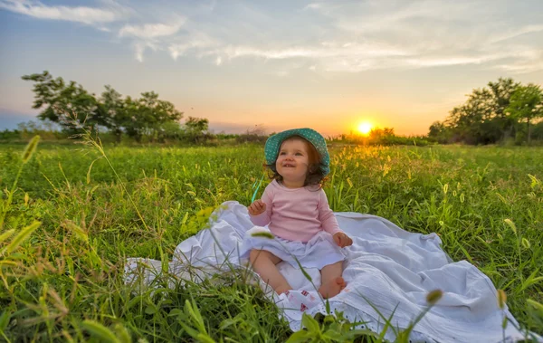 Wunderschönes Baby, das bei Sonnenuntergang auf einer Decke sitzt — Stockfoto