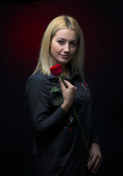 暗い背景に赤いバラと美しい若い女性 — ストック写真