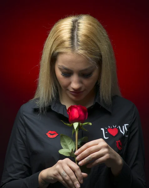 Porträtt av en vacker blond flicka att lukta en röd ros isolerade — Stockfoto