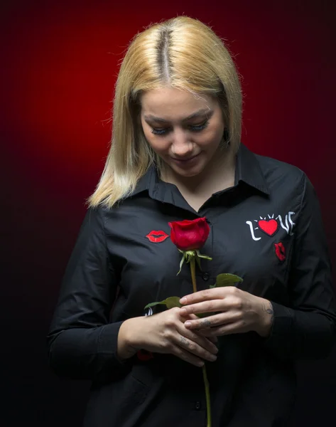 暗い背景に赤いバラと美しい若い女性 — ストック写真