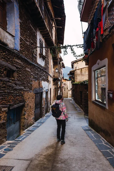 年轻迷人的女性 身穿五颜六色的夹克 站在那里见证着一座古老的小村庄的建筑 — 图库照片