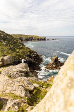 Atlas Okyanusu 'na ve içinde yaşayan vahşi yaşama tanıklık ederken kayanın kenarındaki kayanın tepesinde oturan çekici genç bir dişi.