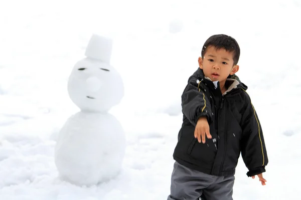 雪合戦と雪だるま (4 歳児を持つ日本男児) — ストック写真