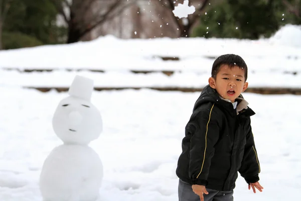 雪合戦と雪だるま (4 歳児を持つ日本男児) — ストック写真