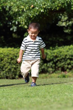 Japon çocuk (3 yaşında çimenlerin üzerinde çalışan)